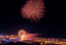 Fogos de artifício coloridos explodindo sobre uma cidade costeira durante a celebração do Ano Novo