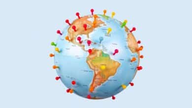 Um globo terrestre com pinos coloridos marcando várias cidades famosas ao redor do mundo, simbolizando viagens internacionais e turismo global.