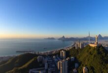 Vista panorâmica da cidade do Rio de Janeiro ao amanhecer, com o Pão de Açúcar e o Cristo Redentor em destaque.