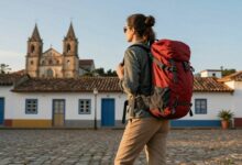 Pessoa apreciando ao pôr do sol em um destino turístico econômico, mochila nas costas, destacando o espírito de aventura e economia durante a viagem.