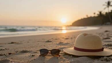 Praia deserta com mala e chapéu ao pôr do sol, simbolizando aventura e relaxamento de uma viagem de última hora