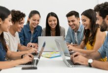 Grupo de pessoas sorrindo planejando uma viagem juntos com mapas e computadores em uma mesa