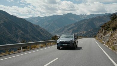 Uma estrada sinuosa com uma bela paisagem de montanhas ao fundo, com um carro moderno viajando por ela, simbolizando a liberdade de uma viagem de carro.